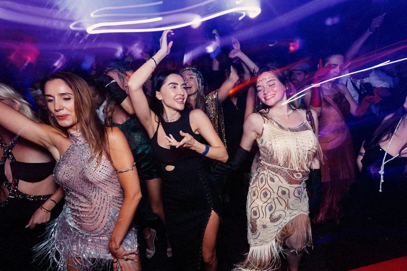 Women in 1920s dresses dancing under streaks of light